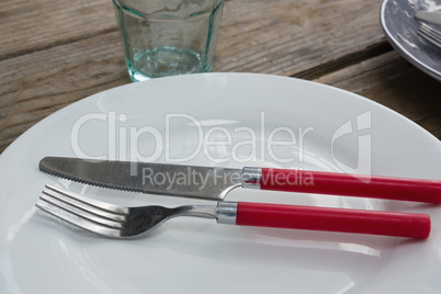 Plate with fork, butter knife and glass on wooden table