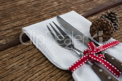 Pine cone with fork, butter knife and napkin tied up with ribbon