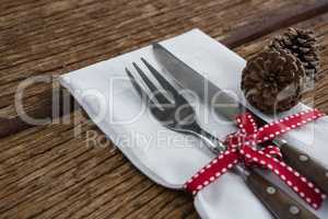 Pine cone with fork, butter knife and napkin tied up with ribbon