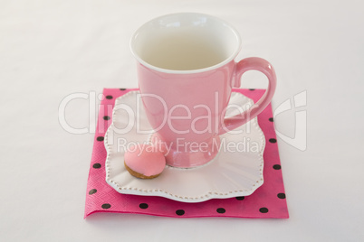 Pink mug with macaron on a dish