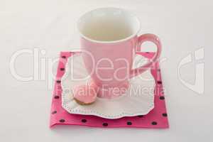 Pink mug with macaron on a dish
