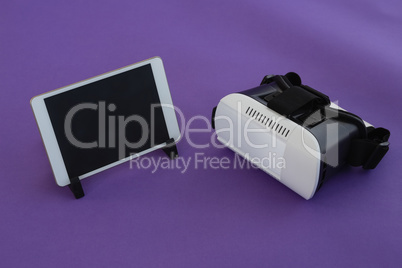Digital tablet and virtual reality headset on purple background