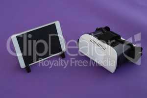 Digital tablet and virtual reality headset on purple background