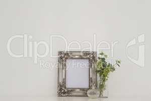 Picture frame, perfume bottle and flora on table