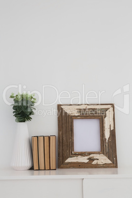 Wooden frame, vase and books arranged on table