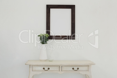 Wooden frame and vase against white wall
