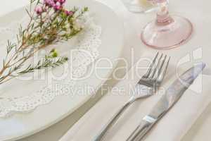 Flower kept over an embroidery napkin plate with cutlery