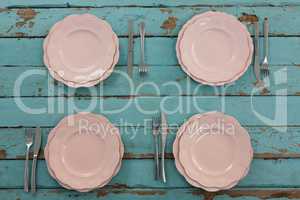 Plates and cutlery arranged on wooden plank