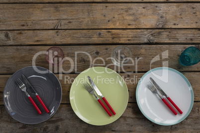 Plates with fork, butter knife and glass on wooden table