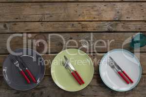 Plates with fork, butter knife and glass on wooden table