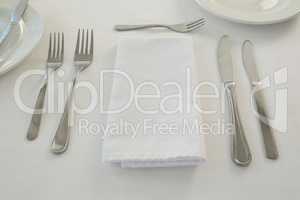 Cutlery with napkin arranged on white background