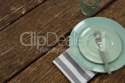 Plate with fork and napkin on wooden table