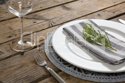Fork, butter knife and wine glass with napkin and herb in a plate