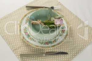 Rose flower in a bowl with cutlery on table cloth