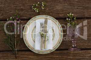 Fork and butter knife with flower and napkin on wooden table