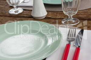 Fork and butter knife with plate on wooden table