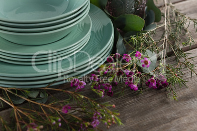 Crockery and floral decorations on wooden plank