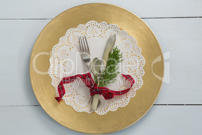 Cutlery with fern tied up with ribbon on a placemat