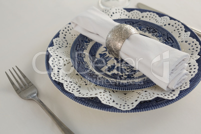 Fork, napkin and lace placemat arranged on white background