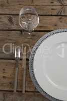 Plate and wine glass with fork and butter knife on wooden table