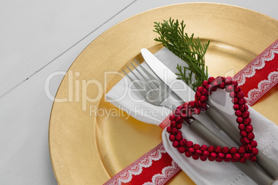 Cutlery with napkin and christmas decoration in a plate