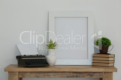 Frame, vase, typewriter and books arranged on table