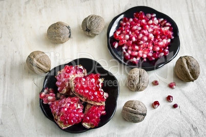 Pomegranate fruits on the plate and walnuts.