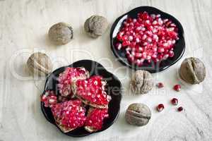 Pomegranate fruits on the plate and walnuts.
