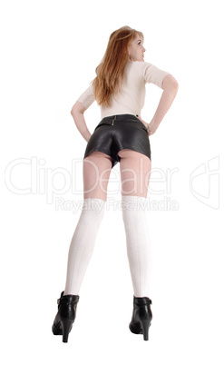 Woman standing in leather shorts from back