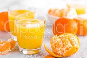 Tangerines, peeled tangerines and tangerine juice in glass. Mandarine juice.