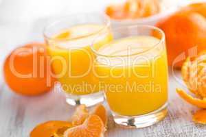 Tangerines, peeled tangerines and tangerine juice in glass. Mandarine juice.