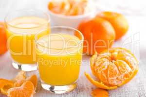 Tangerines, peeled tangerines and tangerine juice in glass. Mandarine juice.