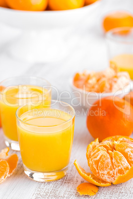 Tangerines, peeled tangerines and tangerine juice in glass. Mandarine juice.