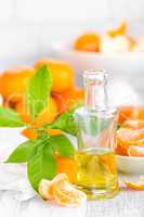 Tangerines with leaves and bottle of essential citrus oil on a white background