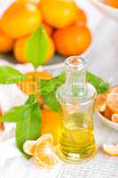 Tangerines with leaves and bottle of essential citrus oil on a white background