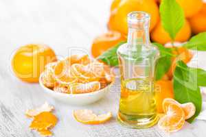 Tangerines with leaves and bottle of essential citrus oil on a white background