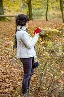 Woman is using her smartphone in the autumn forest