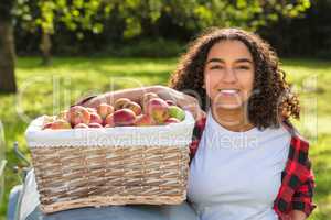 Mixed Race Female Teenager Leaning on Tractor With Apples