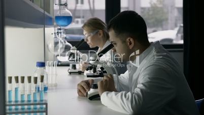 Young scientists studying substance in microscope