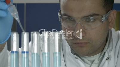 Male scientist with test tubes and pipette in lab