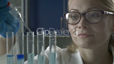 Female scientist dropping liquid into test tubes