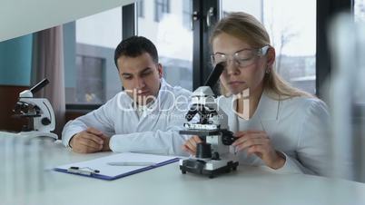 Two focused scientists doing microscope analysis