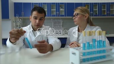 Chemists analyzing test tubes with liquid in lab