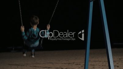 Child swinging on the beach at night