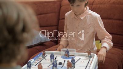 Girl and boy playing table hockey at home