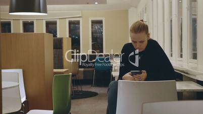 Woman sitting alone in cafe and using mobile