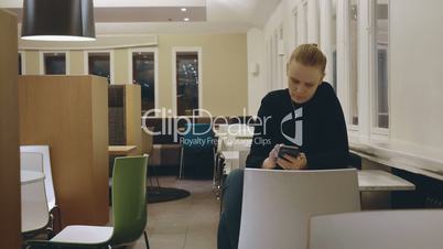Woman in cafe spending lonely evening with mobile