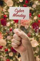 Hand Holding Cyber Monday Card In Front of Decorated Christmas T