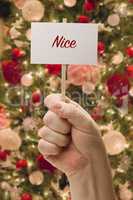 Hand Holding Nice Card In Front of Decorated Christmas Tree.