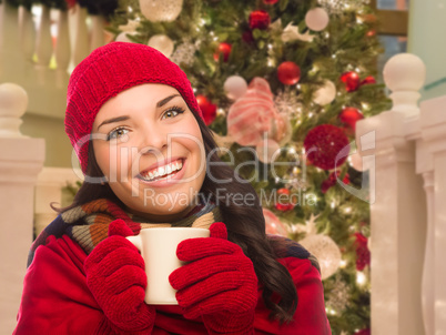 Warmly Dressed Female With Mug In Front of Decorated Christmas T